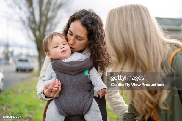 loving mom giving cute toddler girl a kiss while outside walking in neighborhood - asian lesbians kiss stock pictures, royalty-free photos & images