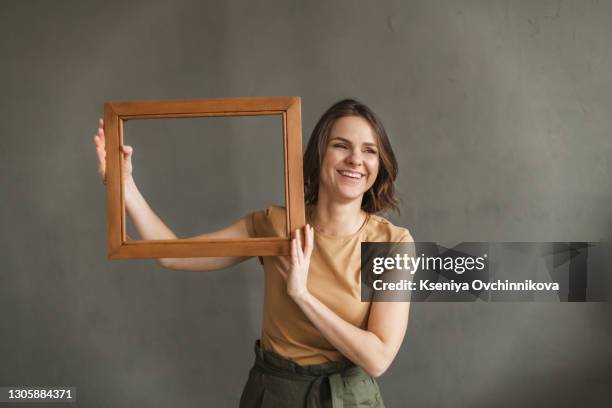 portrait of her she nice-looking cute charming winsome fascinating attractive cheerful cheery wavy-haired lady holding in hands frame comfort cozy life zone isolated over gray background - blank frame stockfoto's en -beelden