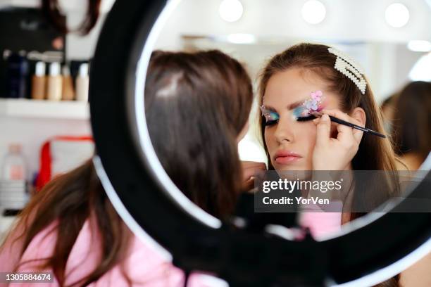 female make-up artist applying make-up on model's face - makeup artist stock pictures, royalty-free photos & images