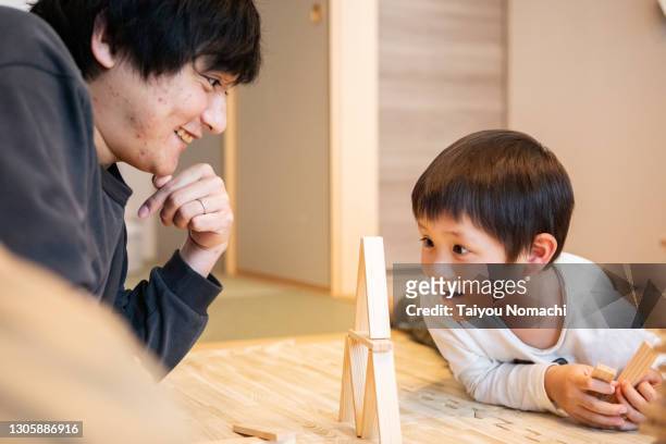 father and son playing with building blocks together - familia de dos generaciones fotografías e imágenes de stock