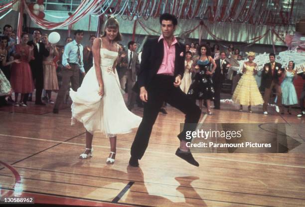 Australian singer and actress Olivia Newton-John and American actor John Travolta dance in a crowded high school gym in a still from the Paramount...