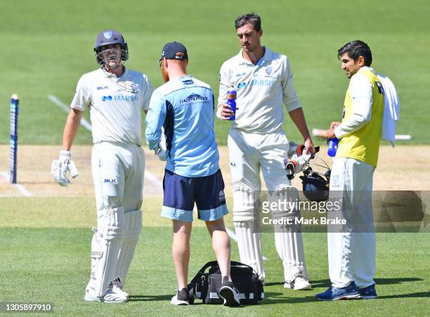 Sean Abbot of the Blues gets treated for cramping in his forearm by the team physio watched by Mitchell Starc of the Blues during day three of the...