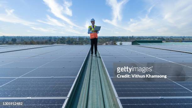 engineers holding tablet standing at solar panels roof - fornitura di energia foto e immagini stock
