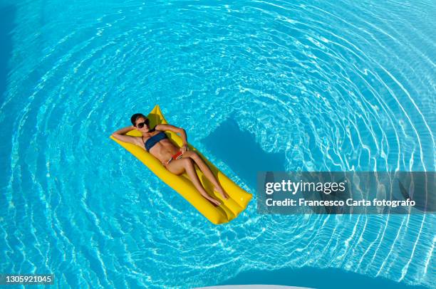 aerial view of woman in swimming pool - luftmatraze stock-fotos und bilder