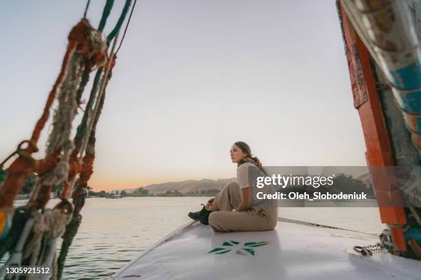 frau auf felucca auf dem nil bei sonnenuntergang unterwegs - nile river stock-fotos und bilder