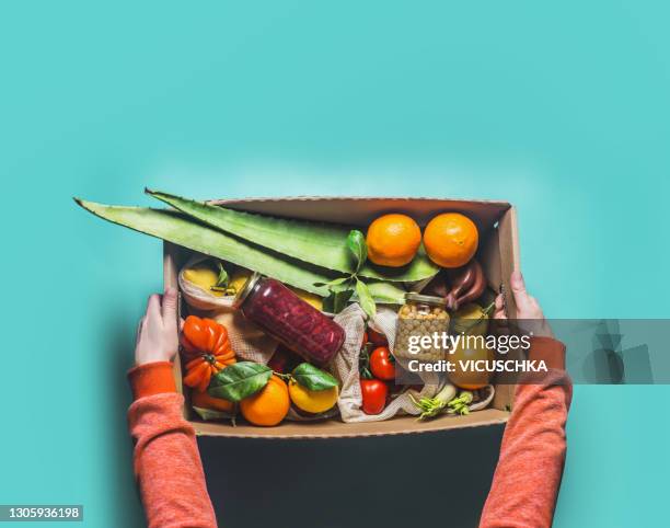 women hands in red sweatshirt holding eco-friendly paper shopping box with various healthy groceries - food box stock-fotos und bilder