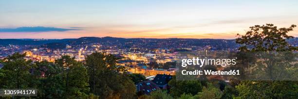 germany, baden-wurttemberg, stuttgart, panorama of illuminated city center seen from top of uhlandshohe hill at dusk - stuttgart panorama stock pictures, royalty-free photos & images