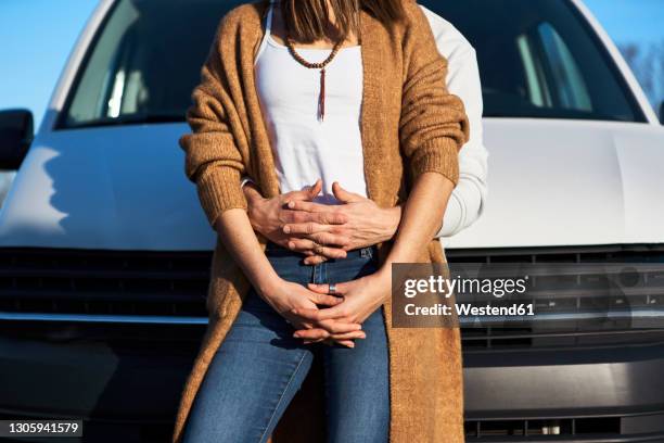 boyfriend embracing girlfriend from behind while leaning on car - hugging mid section stock pictures, royalty-free photos & images