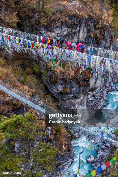 group of trekkers crossing suspension bridge near namche bazaar, mount everest national park - nepal water stock pictures, royalty-free photos & images