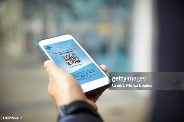 businessman having online covid-19 vaccine passport - airport smartphone stock-fotos und bilder