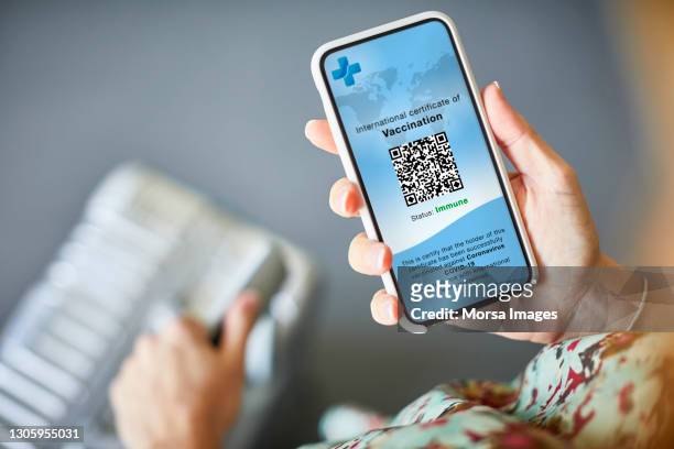 woman checking covid-19 vaccine passport on cellphone - phone screen at airport stockfoto's en -beelden