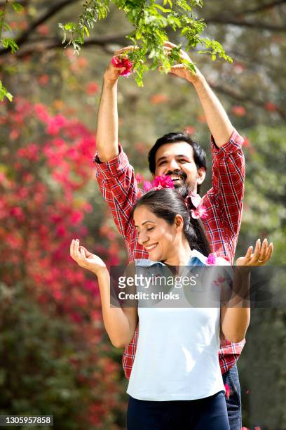 man showering flower petals on woman at park - bonding stock pictures, royalty-free photos & images