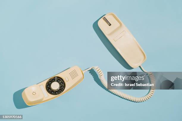 from above of a yellow rotary dial telephone off the hook on a blue background. - antique phone photos et images de collection