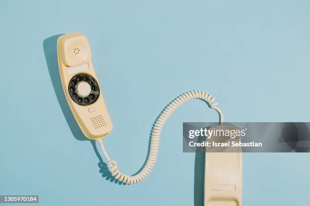 from above of a yellow rotary dial telephone off the hook on a blue background. - teléfono con cable fotografías e imágenes de stock