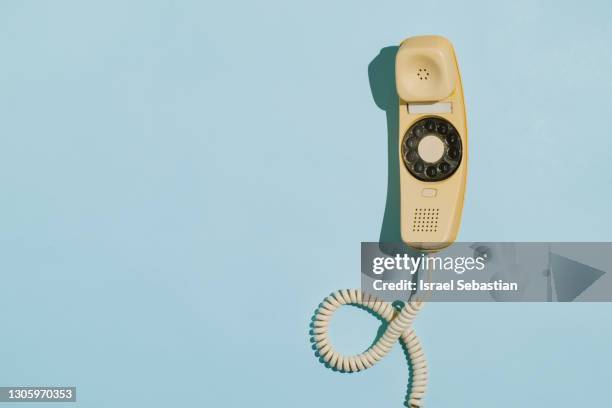 close-up of the handset of a yellow telephone off the hook on a blue background - 90s cell phone bildbanksfoton och bilder