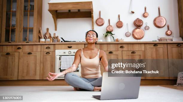 de jonge latijnse vrouw met vitiligo maakt yoga bij keukenvloer voor laptop - bemiddeling stockfoto's en -beelden