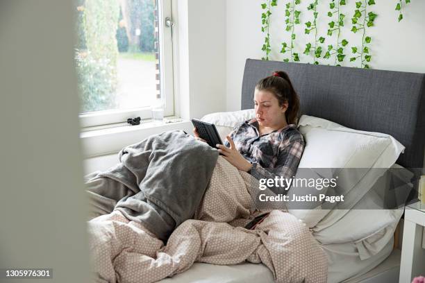 teenage girl using digital tablet in bed - skin rash stock pictures, royalty-free photos & images