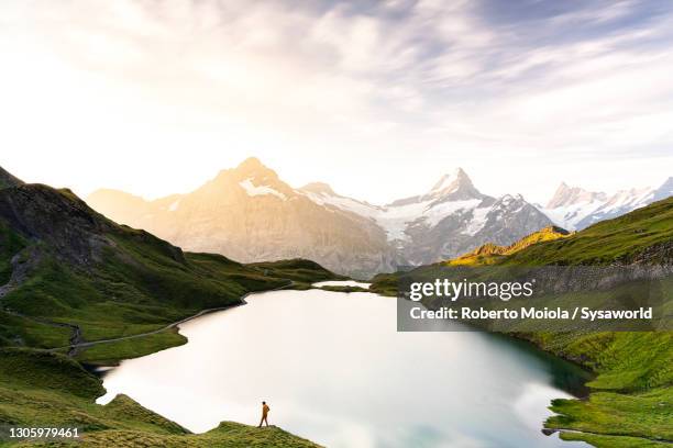 hiker in the mist at dawn at bachalpsee lake, switzerland - morning in the mountain fotografías e imágenes de stock