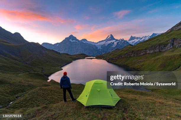 man with tent at bachalpsee lake at dawn, switzerland - grindelwald stock pictures, royalty-free photos & images