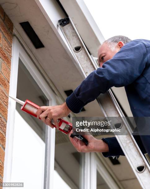 senior man putting sealant around leaking windows - january 2021 stock pictures, royalty-free photos & images