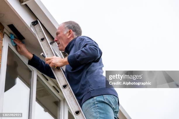 senior man cleaning and putting sealant around leaking windows - january 2021 stock pictures, royalty-free photos & images