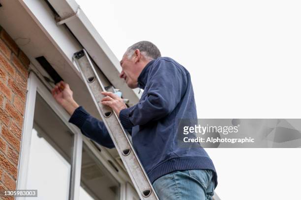 senior man cleaning and putting sealant around leaking windows - january 2021 stock pictures, royalty-free photos & images