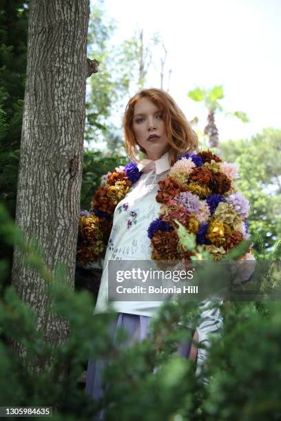 mujer joven pelirroja posando sobre árbol con chaqueta de flores - chaqueta rosa stock-fotos und bilder