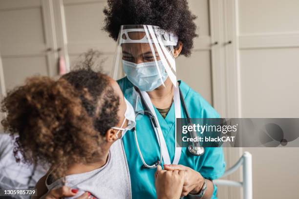 female doctor consoling little girl wearing face mask during home visit - cat face mask stock pictures, royalty-free photos & images