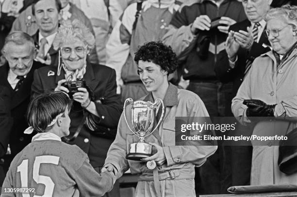 United States player accepts the trophy after the United States team beat England 19-9 in the final of the 1991 Women's Rugby World Cup tournament to...