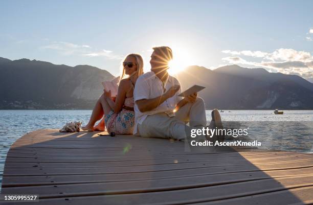 couple read together on end of dock over lake, sunrise - early retirement stock pictures, royalty-free photos & images