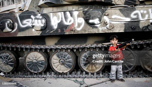 Young boy stands in front of a Gaddafi loyalist tank smashed by NTC forces in Tripoli Street on September 08, 2011 in Misrata, Libya. NTC forces are...