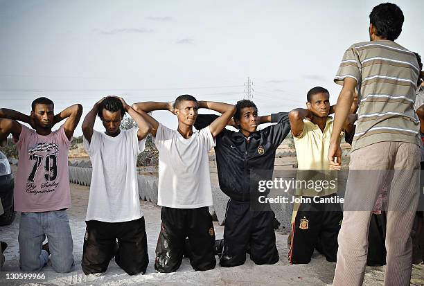 Militia fighters loyal to Gaddafi are captured and taunted by Misratan NTC fighters near Colonel Gaddafi's home city of Sirte on September 20, 2011...