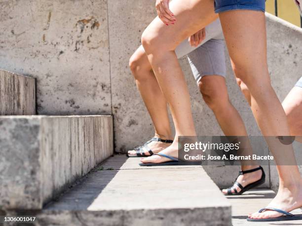 group of young teenagers with shorts and sandals walking along the streets of the city in summer. - girl sandals stock pictures, royalty-free photos & images