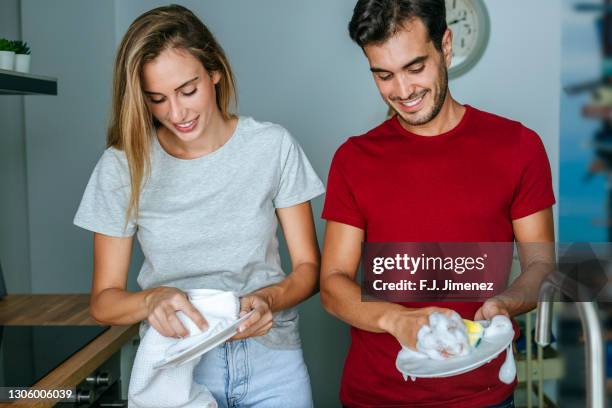 couple indoors washing dishes - tarea doméstica fotografías e imágenes de stock