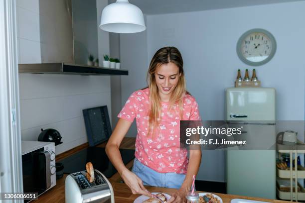 woman having breakfast in home kitchen - een broodje smeren stockfoto's en -beelden
