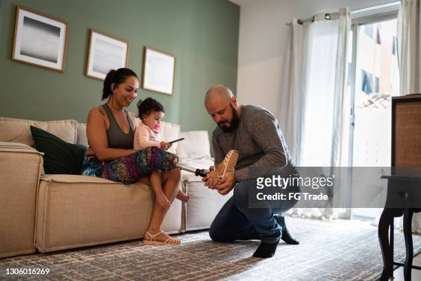 woman with disability being helped by her husband wearing shoes at home - amputee home stock pictures, royalty-free photos & images
