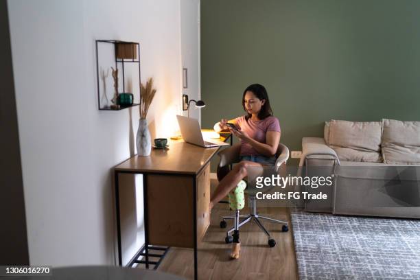 Young woman with disability using smartphone while working at home