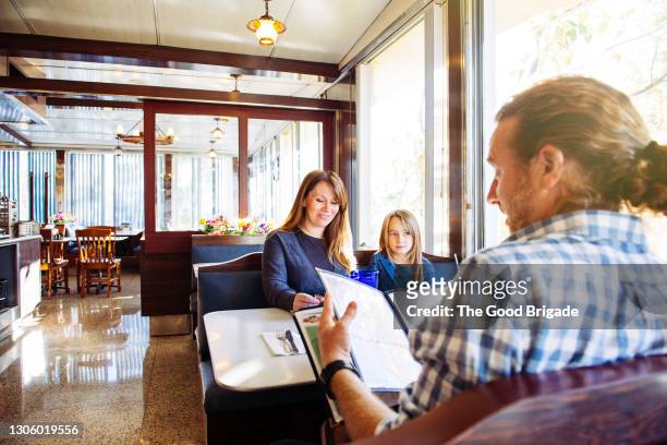 mother and father looking at menu in diner with daughter - family decisions stock pictures, royalty-free photos & images