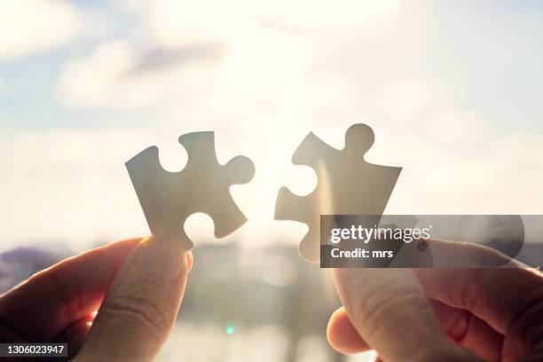 hands trying to fit two puzzle pieces together - part of team stock pictures, royalty-free photos & images