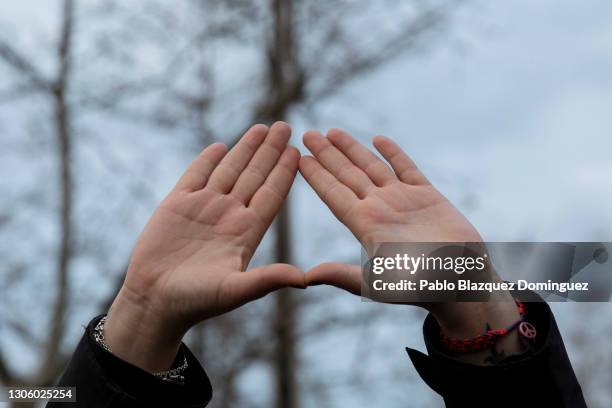 Women's rights supporter gives a feminist hand symbol during a gathering after a mural celebrating a diverse array of women was vandalized today with...