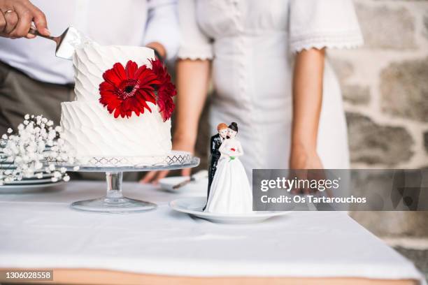 bride and groom figurines on a plate over the table where a small wedding cake that is being cut - wedding cake cutting stockfoto's en -beelden