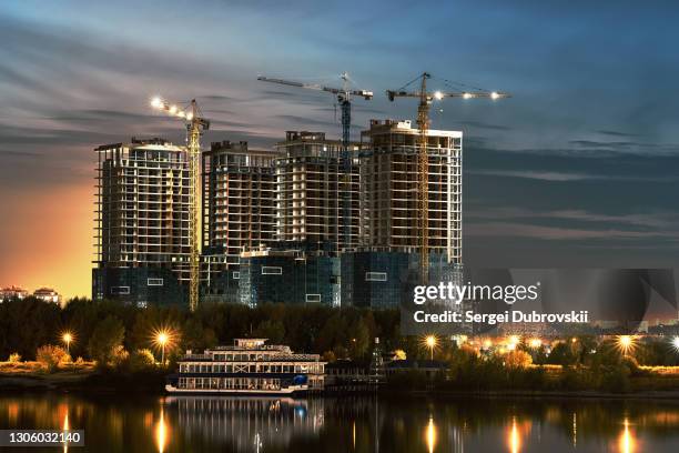 construction site with new buildings and cranes at evening blue yellow cloudy sky background - silouhette construction work stock pictures, royalty-free photos & images