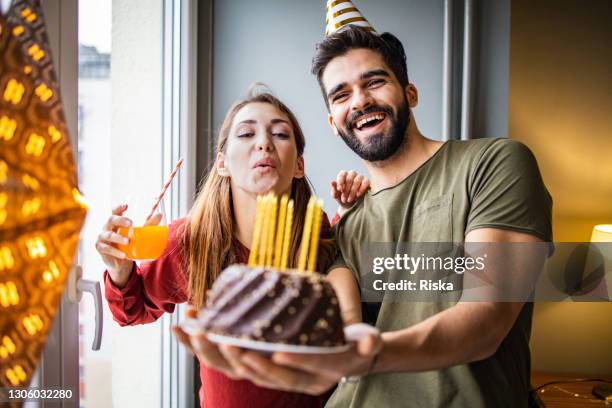 romantic couple with a birthday cake, having a celebration at home - holding birthday cake stock pictures, royalty-free photos & images