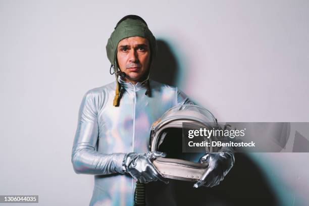 man wearing silver tight suit and retro astronaut helmet in hands - cosmonaut stock pictures, royalty-free photos & images