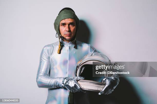 man wearing silver tight suit and retro astronaut helmet in hands - cosmonaut imagens e fotografias de stock