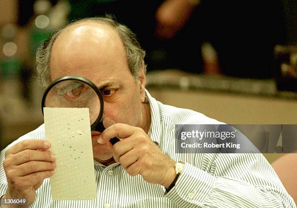 Judge Robert Rosenberg of the Broward County Canvassing Board uses a magnifying glass to examine a dimpled chad on a punch card ballot November 24,...