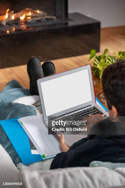 over the shoulder view, woman on laptop by fireplace. - computer screen over shoulder stock pictures, royalty-free photos & images