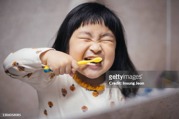happy little girl brushing her teeth in the bathroom - toothpaste stock-fotos und bilder