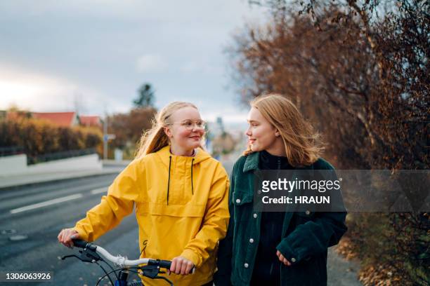 teenage girls walking outdoors with a bike - 14 year old blonde girl stock pictures, royalty-free photos & images