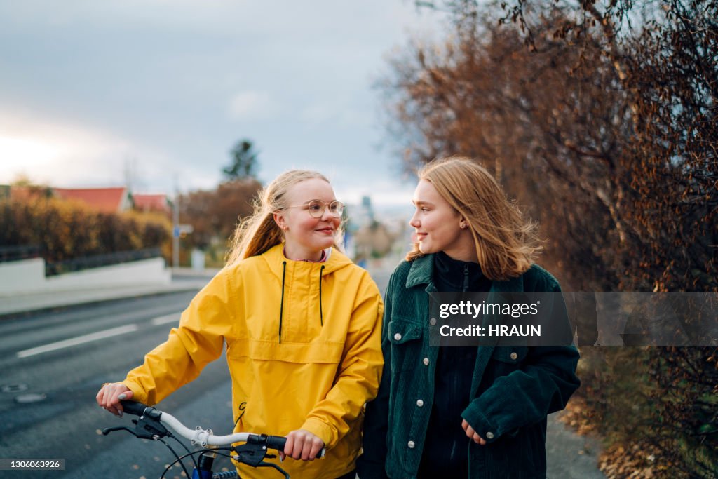 Tonårsflickor som går utomhus med en cykel
